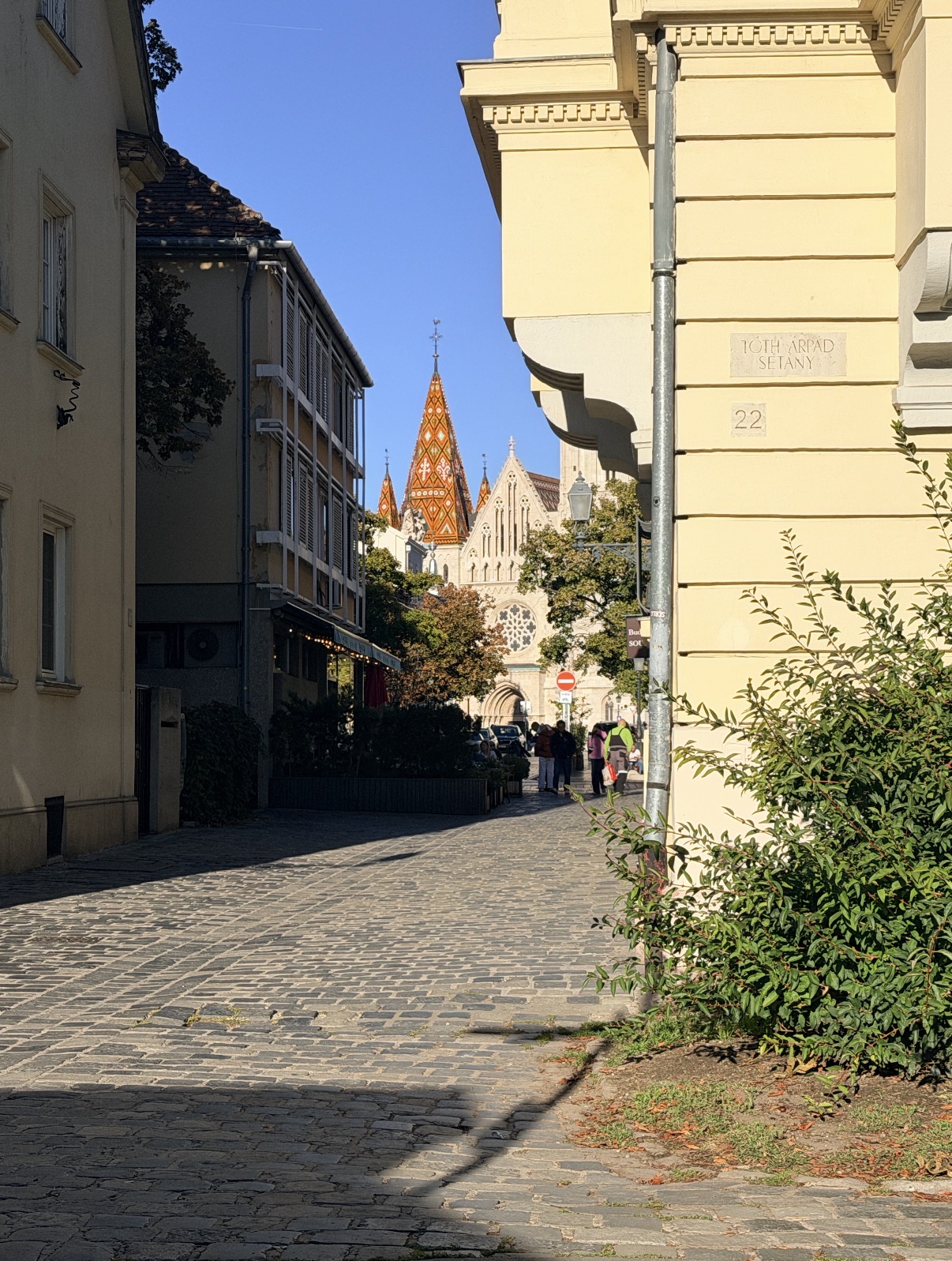 A cobblestone street with a colorful church roof in the distance